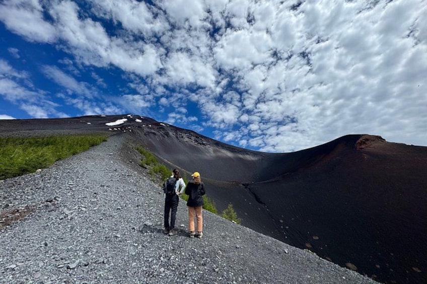 Dos personas de pie sobre un sendero de grava con una montaña al fondo. 1