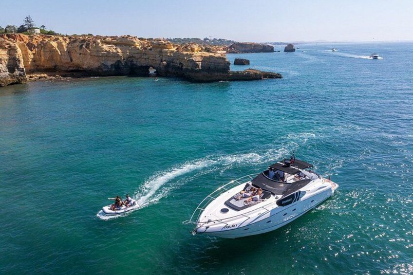 A large yacht and a smaller boat on a calm sea with rocky cliffs in the background. 3
