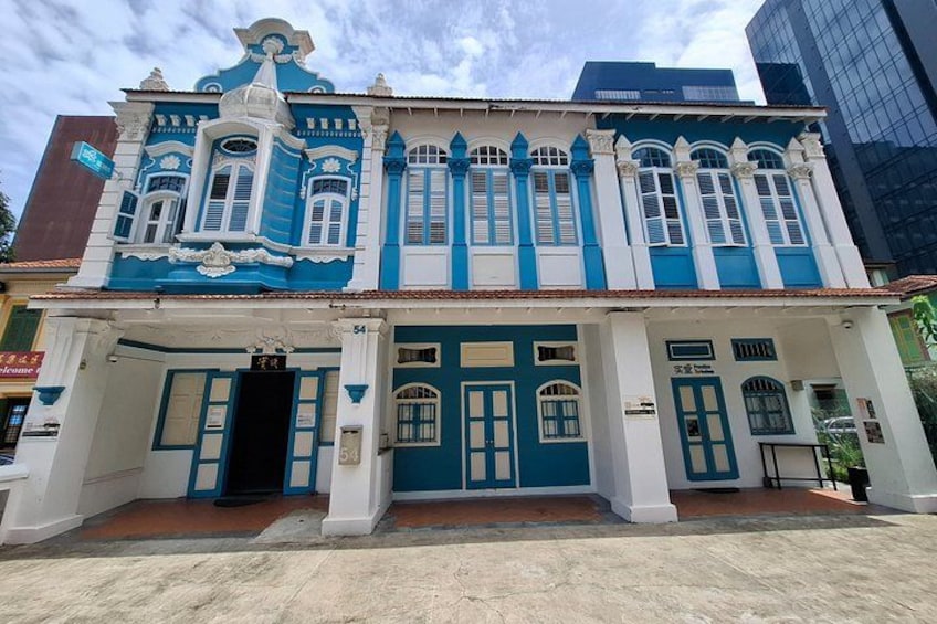 Ein traditionelles Gebäude mit blau-weißer Fassade, verzierten Fenstern und einem Ziegeldach. 4