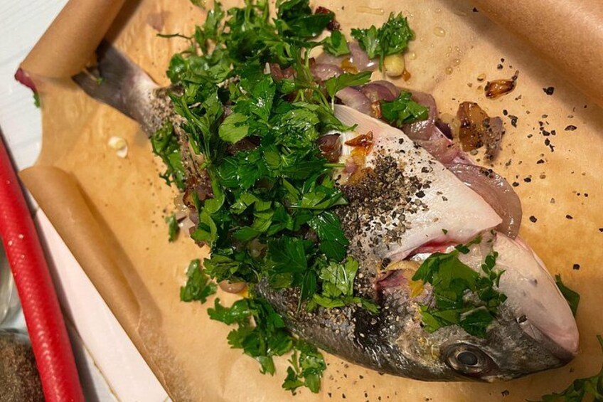 A whole fish garnished with herbs and spices, placed on parchment paper. 5