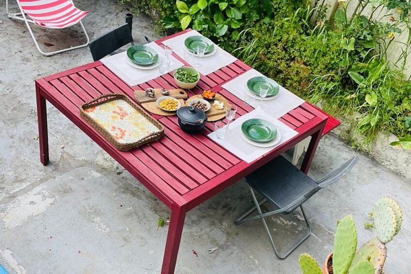 A red wooden table set outdoors with green plates, bowls, and a casserole dish. 3