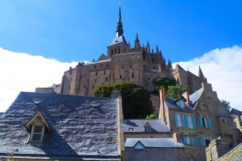 A historic castle with a prominent tower, surrounded by traditional buildings with blue shutters. 2