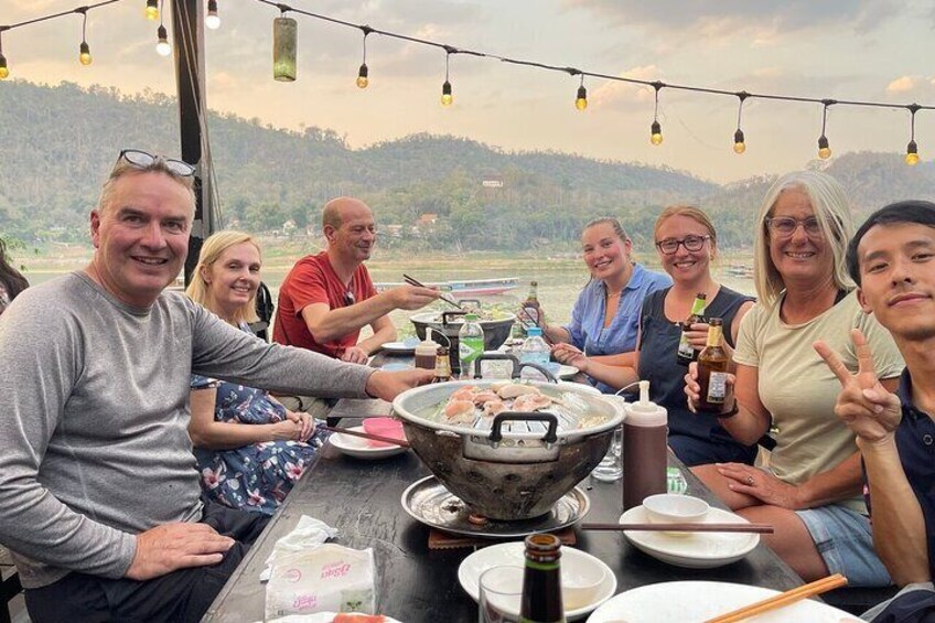 Un grupo de personas sentadas alrededor de una mesa con una parrilla, disfrutando de una comida al aire libre. 5