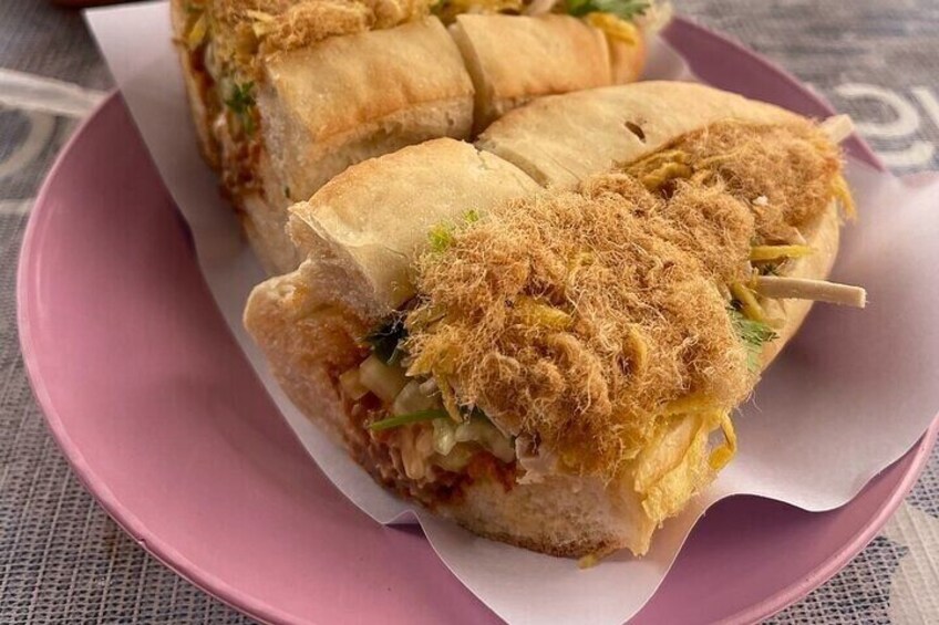 Un sándwich con cobertura crujiente, sobre un plato rosa. 2