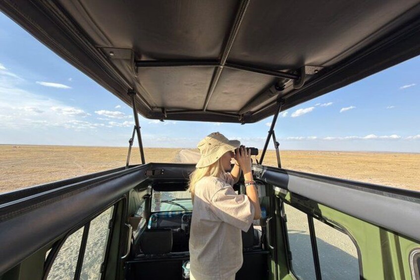 Una persona en un vehículo con techo abierto fotografiando un paisaje extenso y llano. 3