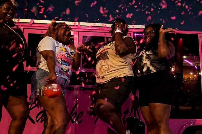 People dancing in a pink-lit venue with a pink wall and a sign that says 'I can be me.' 2