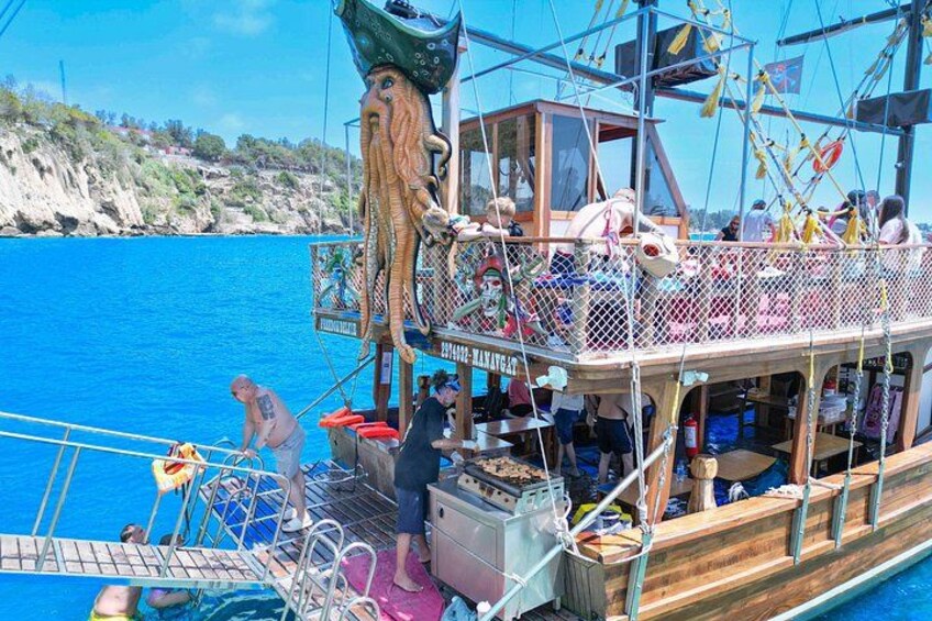 A boat with a wooden deck, a figurehead resembling a sea creature, and a rocky coastline in the background. 5