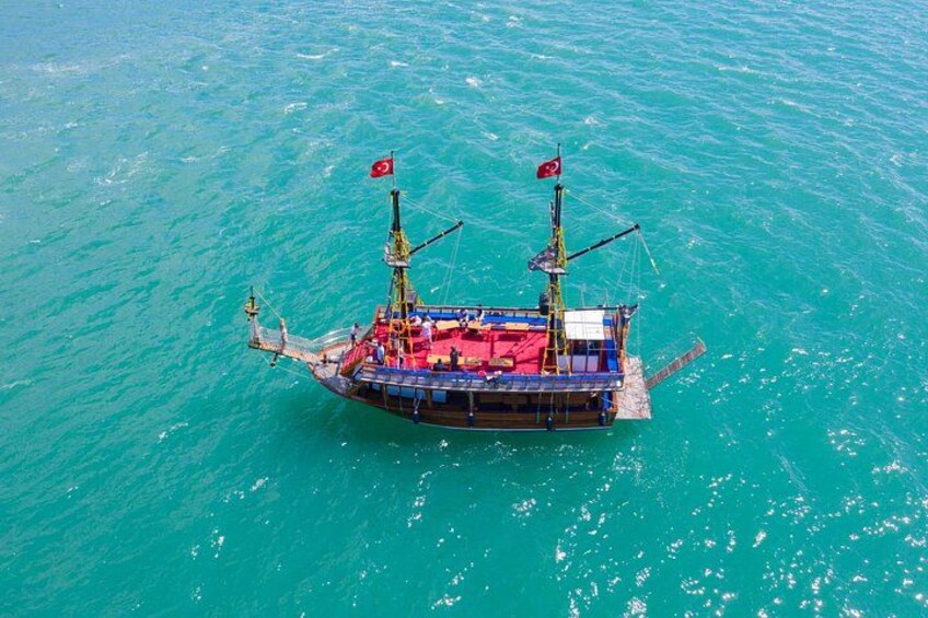 A large ship with two flags, floating on turquoise water. 2