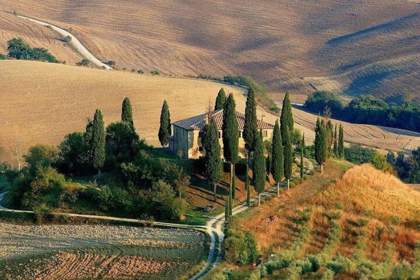 A rural landscape with rolling hills, a winding road, and a traditional building surrounded by trees. 5