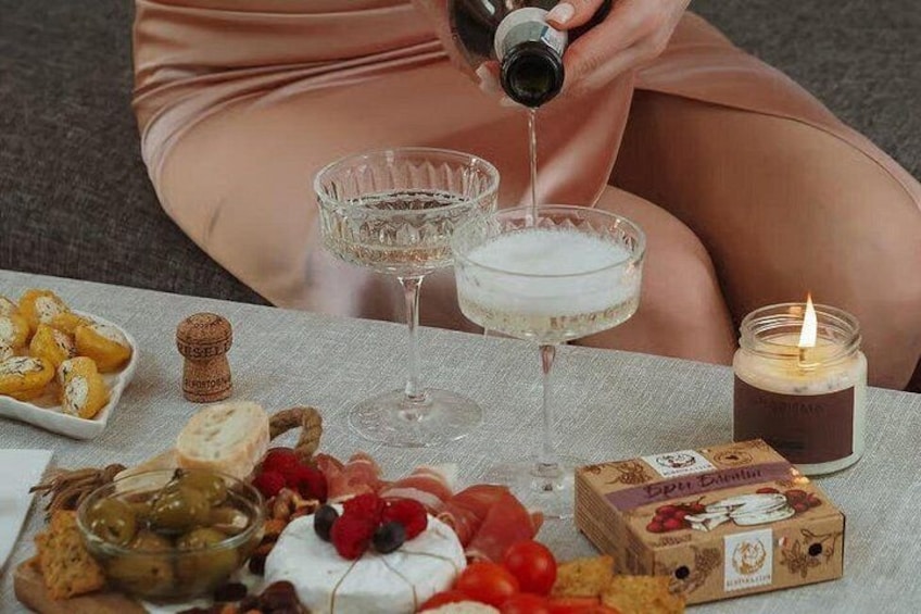 A table with a variety of food items, a candle, and a bottle being poured into a glass. 3