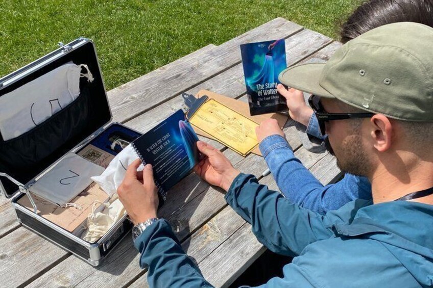 Una persona legge un libro a un tavolo di legno all'aperto. 2