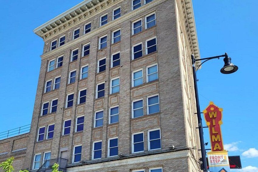 A multi-story brick building with a large marquee sign on the corner. 2
