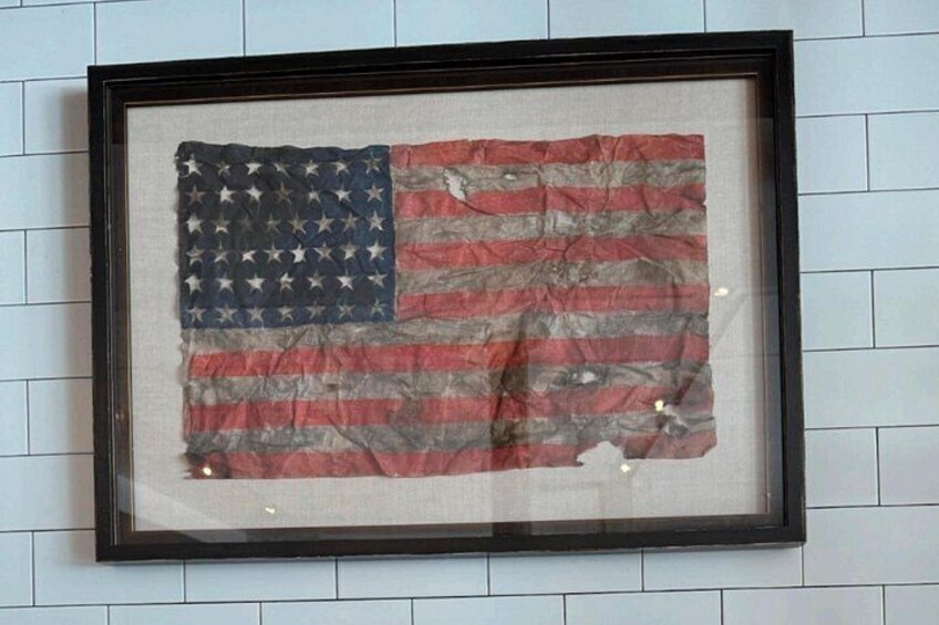 A framed American flag with visible wear and tear. 4