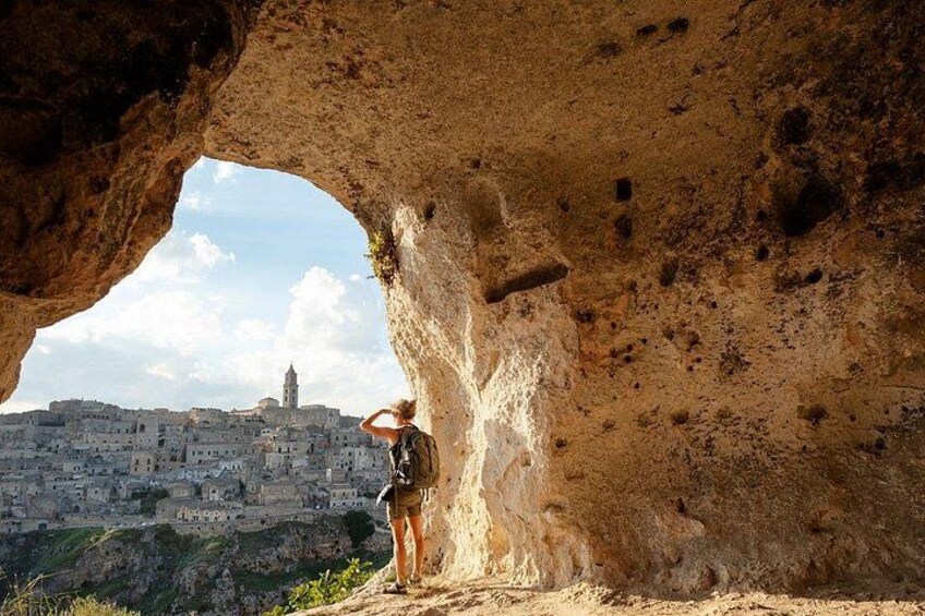 A person standing in a cave with a view of a cityscape. 1
