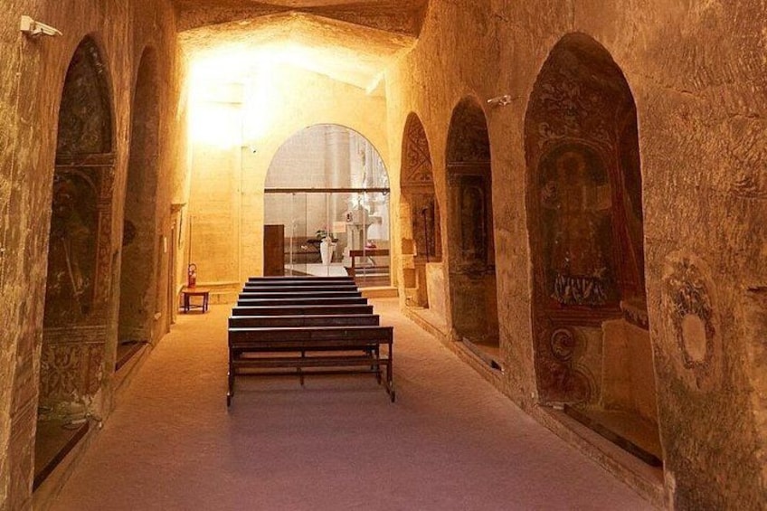 A dimly lit corridor with arched ceilings and a central bench. 3