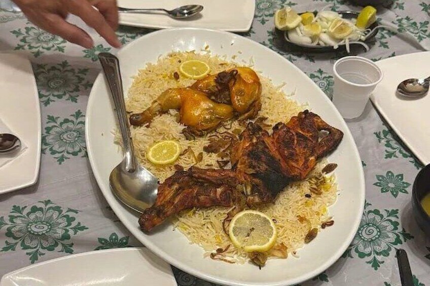 Een bord biryani met kip, versierd met partjes citroen. 4