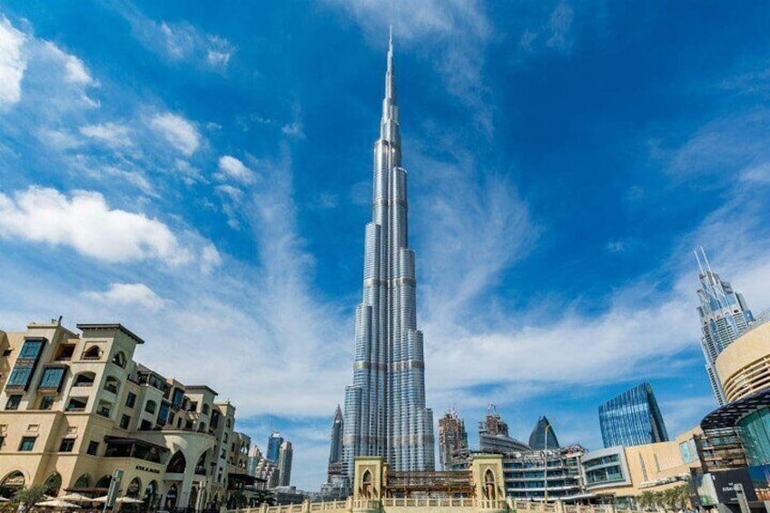 De Burj Khalifa, een hoge wolkenkrabber, omgeven door andere gebouwen en een heldere blauwe lucht. 1