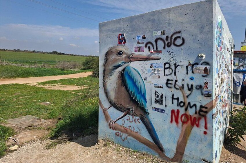A concrete block with a bird mural, graffiti, and stickers. 4