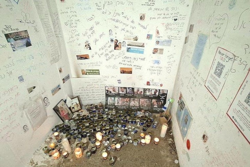 A room with walls covered in handwritten notes and photos, a floor scattered with bottles, and a shelf with framed pictures. 5