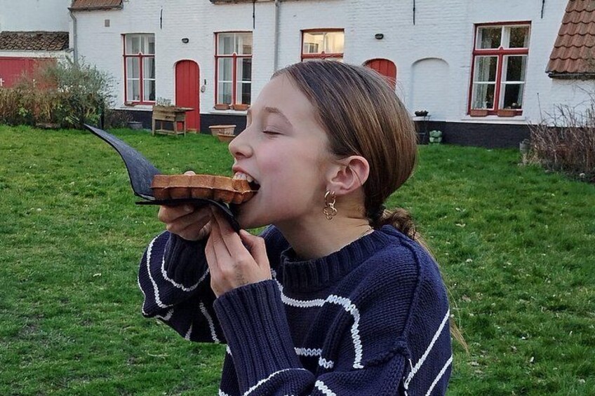 A person eating a sandwich outdoors with a house in the background. 5
