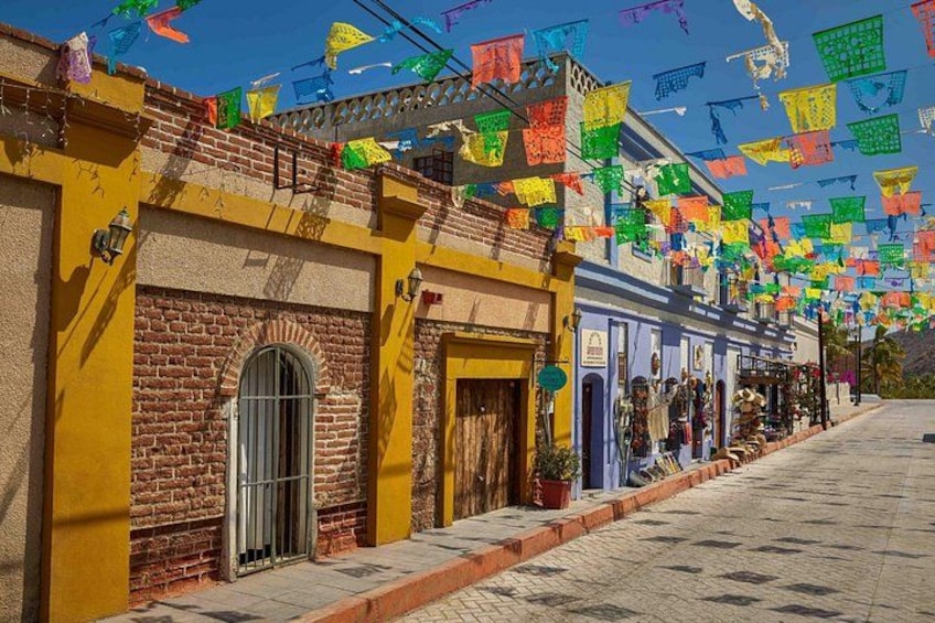 A street lined with colorful buildings, a clear blue sky, and hanging decorations. 3