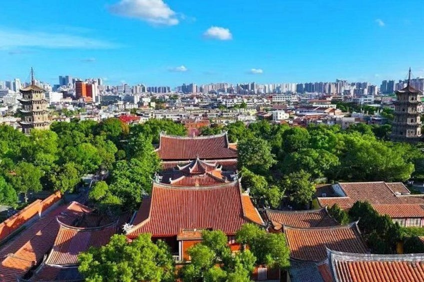 A traditional Chinese pagoda surrounded by lush greenery, with a modern cityscape in the background. 5