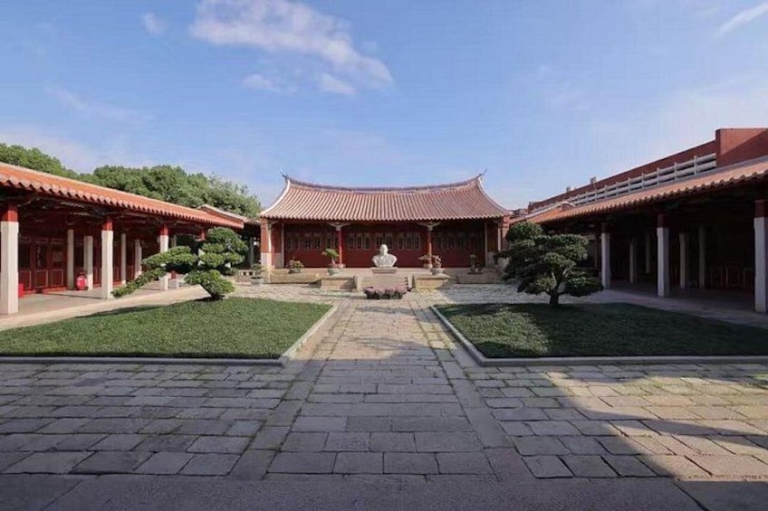 A traditional courtyard with tiled roofs, stone pathways, and neatly trimmed bushes. 4
