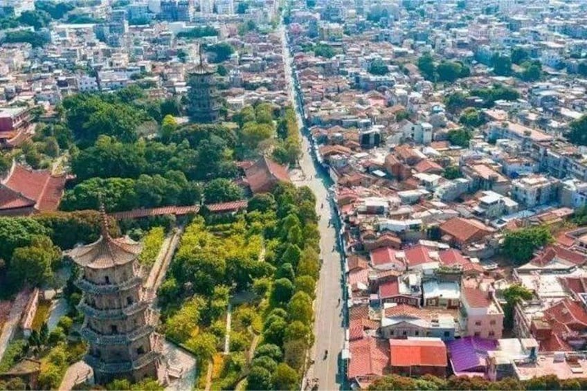 An aerial view of a city with a prominent pagoda, dense residential areas, and a river running through the center. 2