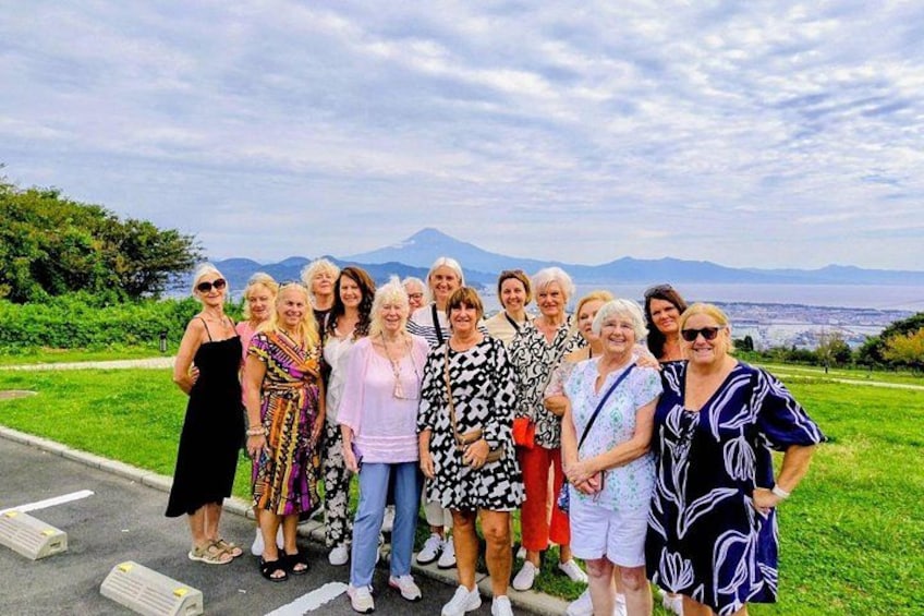 Eine Gruppe von Menschen steht an einer Straße mit einem reizvollen Blick auf Berge und grüne Landschaft im Hintergrund. 2