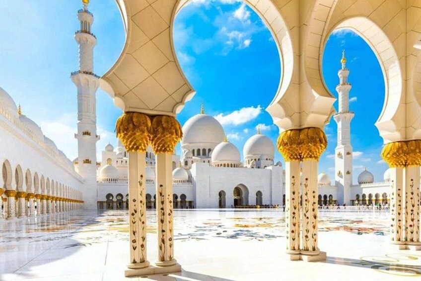 Eine Moschee mit weißen Kuppeln und goldenen Bögen. 2