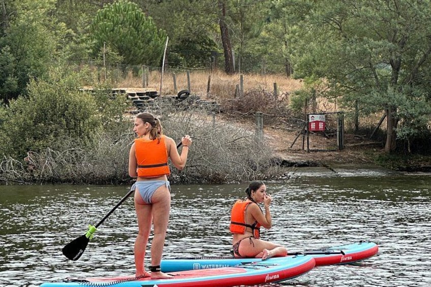 Two people on a paddleboard in a river surrounded by trees. 2