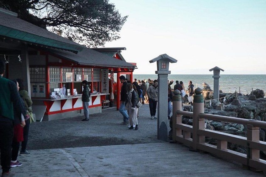 A coastal walkway with people, a traditional red and white building, and a stone railing. 5