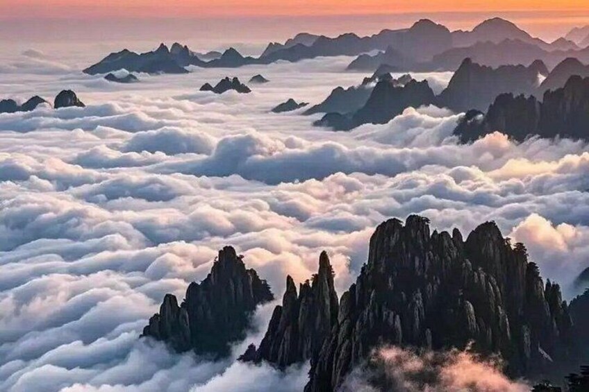 A mountainous landscape with cloud-covered peaks and a sunrise or sunset. 1