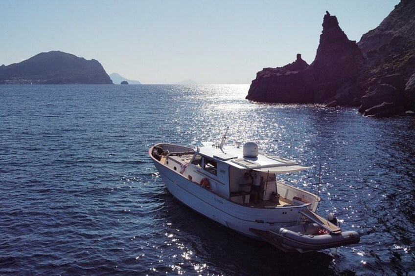A boat on calm waters near rocky cliffs under a clear sky. 2