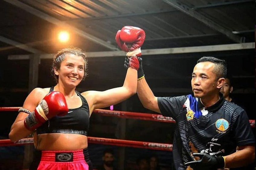 A boxing ring with a person wearing red gloves and a black top. 2