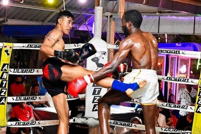 A boxing match in progress with two fighters in a ring, one delivering a high kick. 5