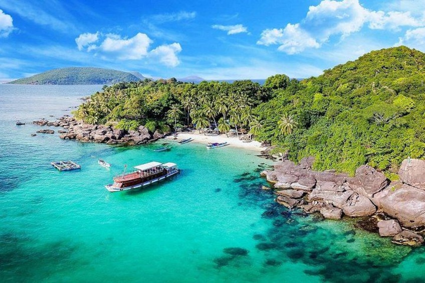 Una playa tropical con aguas turquesas cristalinas, un bote y colinas verdes exuberantes. 1