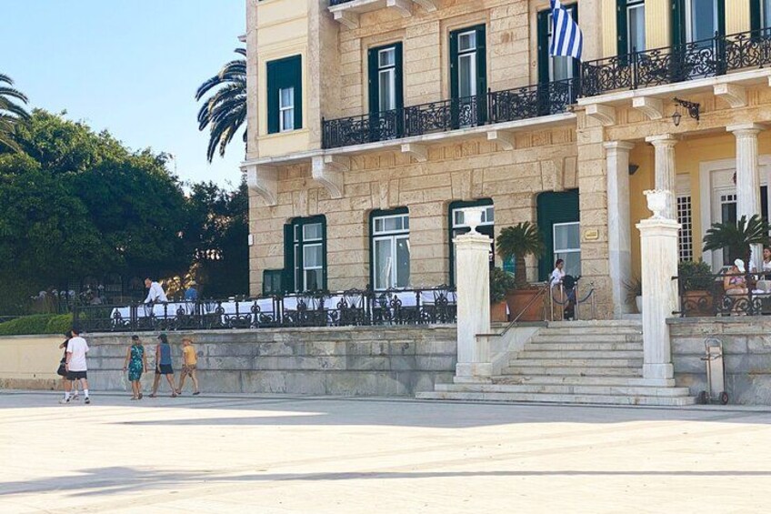 A historic building with columns, a balcony, and a flag. 3