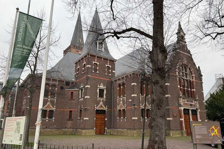 Een historisch gebouw met een opvallende toren en een grote houten deur. 2