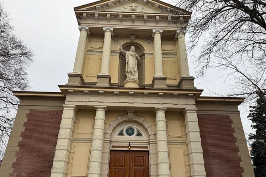 Een kerk met een centraal beeld, een klok en een grote houten deur. 5