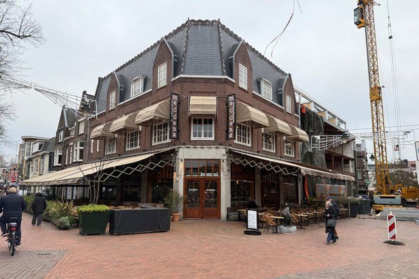 Een historisch gebouw met een overdekte ingang, terras en een bouwkraan in de buurt. 3