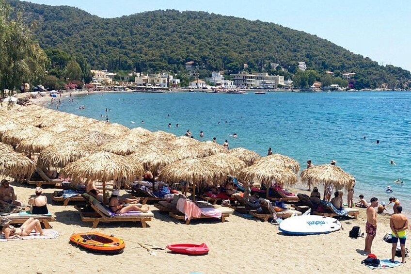 A beach with umbrellas, lounge chairs, and people swimming. 2
