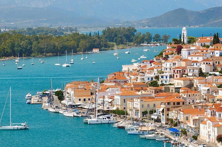 A coastal town with buildings, boats, and a clear blue sea. 1