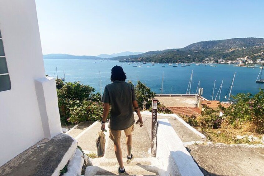 A person descending a staircase towards a coastal view with boats and hills in the background. 3