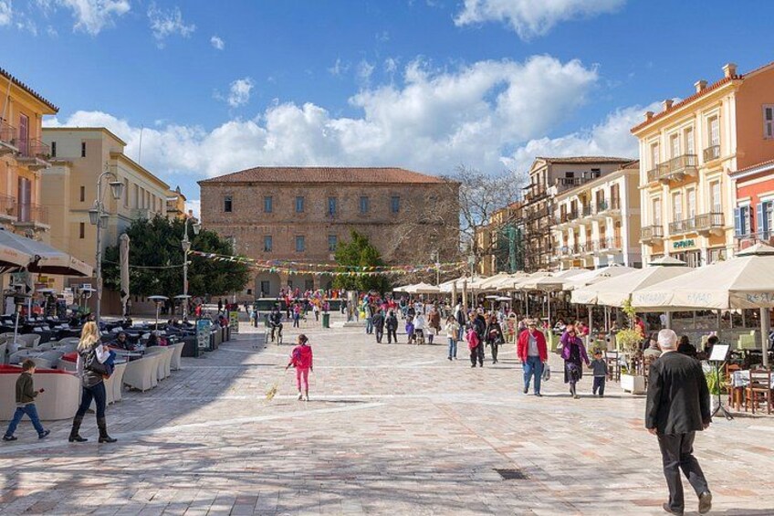 A bustling square with outdoor cafes, people walking, and historic buildings. 4