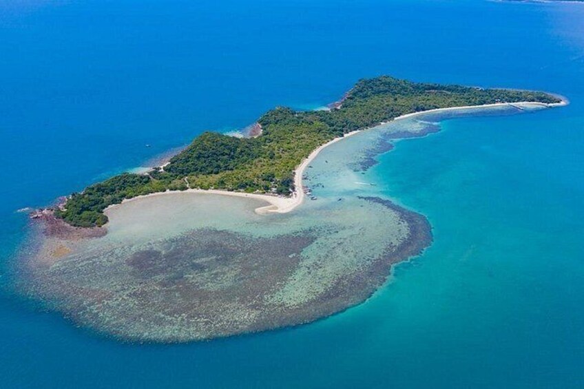 An aerial view of a coastal island with a curved shoreline, clear blue waters, and a dense green forest. 2