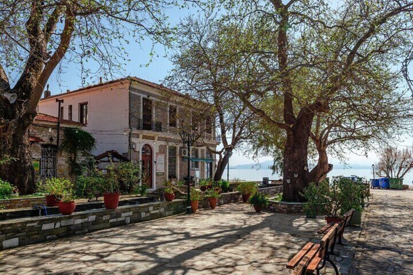 A historic building with a balcony, surrounded by potted plants and a bench. 4