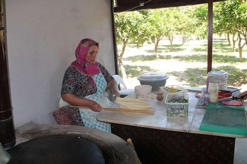 A person preparing food outdoors with a table full of cooking utensils and ingredients. 2
