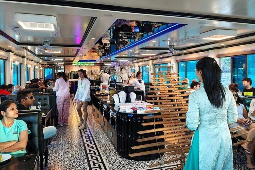 Ein Speisesaal auf einem Kreuzfahrtschiff mit Passagieren an Tischen, einer Bar und einem Buffet. 1