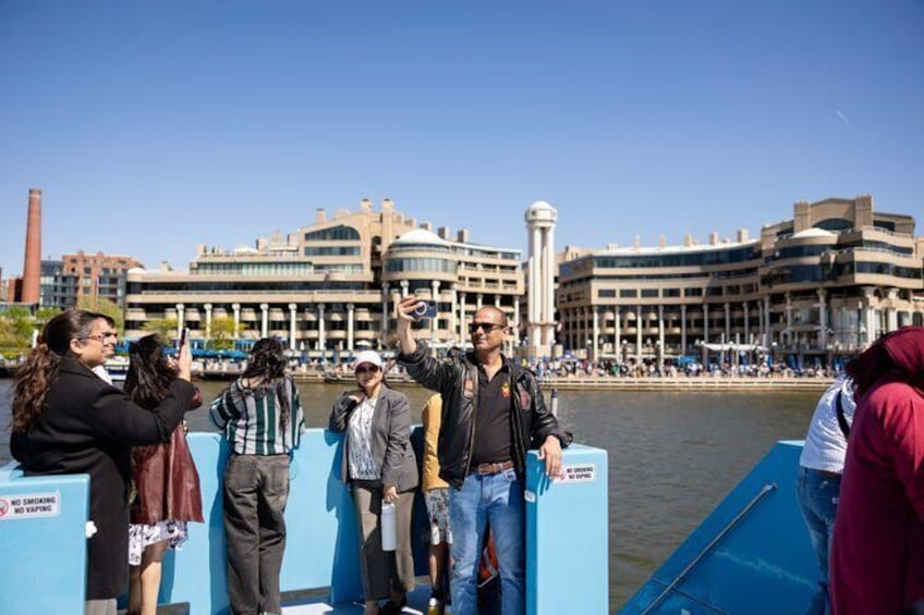 People on a boat near a waterfront with buildings in the background. 1